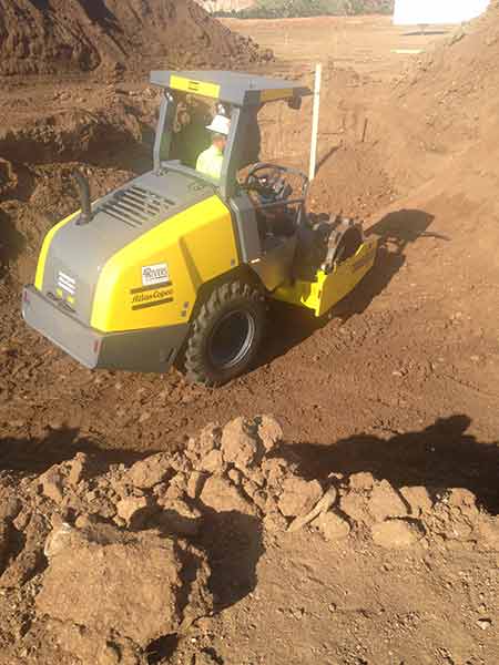 compactor operator working surrounded by mounds of dirt